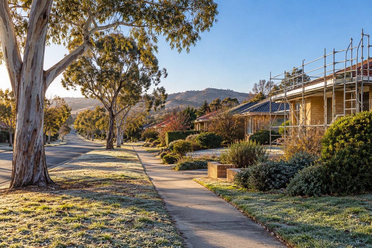 A quiet suburban Canberra street on a frosty morning, brick and tile houses from the 1970s and 80s, one with a scaffold across its front, wide nature strips with ghost gums and hills beyond